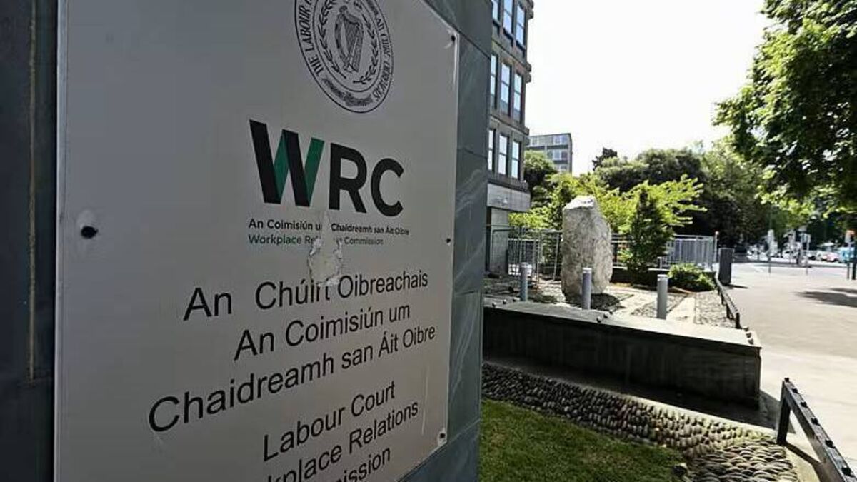 Exterior of a building with WRC logo, Irish text, and landscaped courtyard with trees and stone wall.