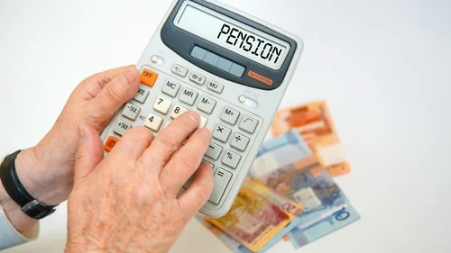 Hand pressing buttons on a calculator labeled PENSION, with banknotes blurred in background.