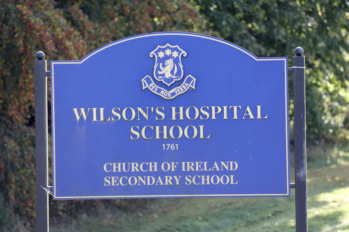 Blue sign reading “Wilson’s Hospital School” with crest and “Church of Ireland Secondary School” text.