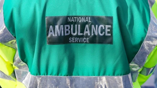Green national ambulance service jacket with reflective stripes and a visible “AMBULANCE SERVICE” patch.